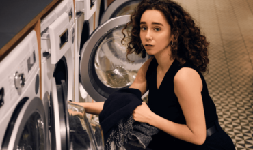 Woman using commercial laundry equipment.