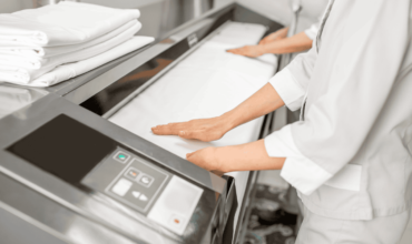 Staff operating automatic ironing machines to press and fold linens.