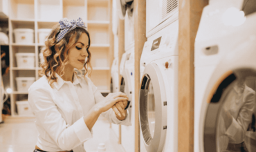 Woman operating a commercial tumble dryer in a laundry facility.