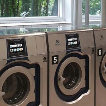 Advanced Commercial Laundry Setup with Efficient Tumble Dryers and Automatic Ironing Machines.