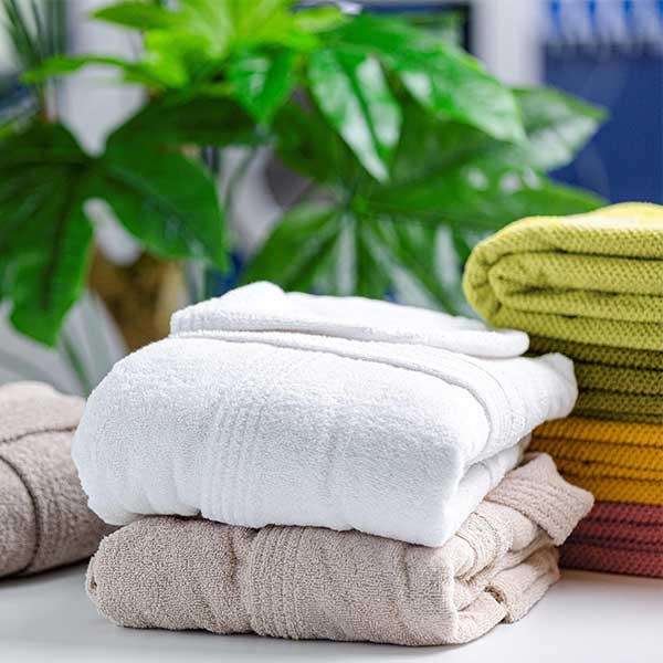 Freshly Laundered Towels with Commercial Tumble Dryer and Automatic Ironing Machines in Commercial Laundry Equipment Setup