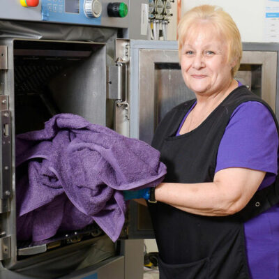 This image displays a professional using Commercial Laundry Equipment, highlighting its capacity for handling large loads efficiently, ideal for institutional laundry needs.