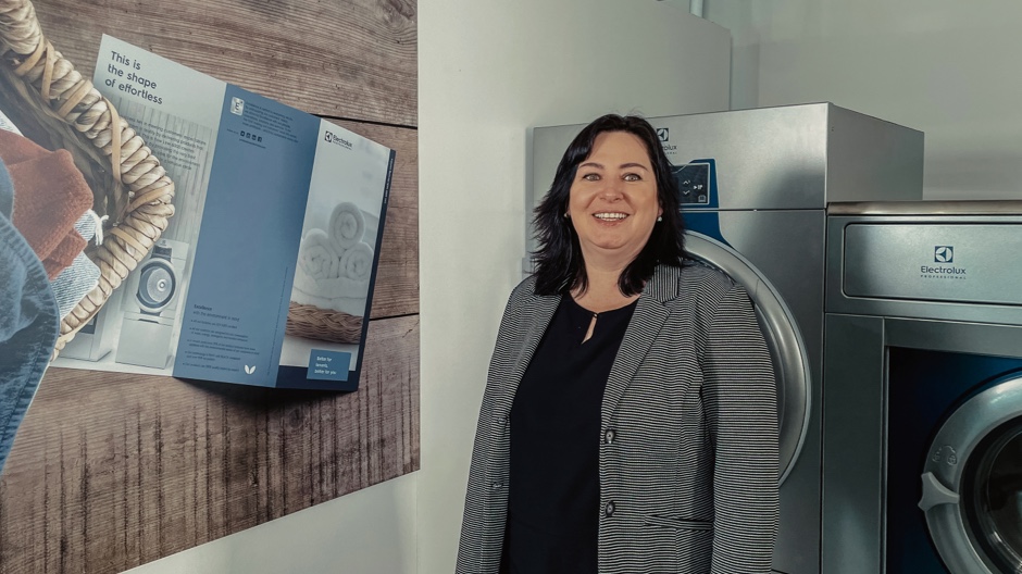 Woman beside commercial laundry machines