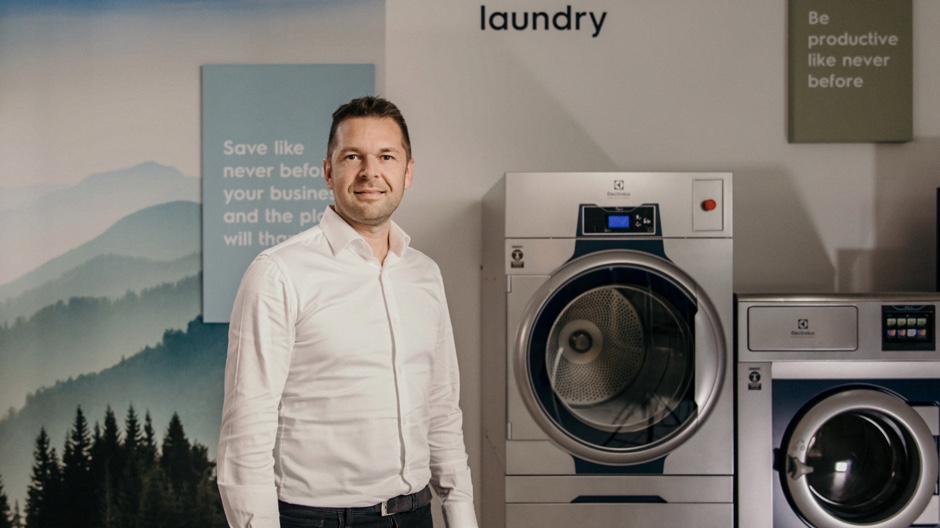 Man standing beside high-tech commercial laundry machines