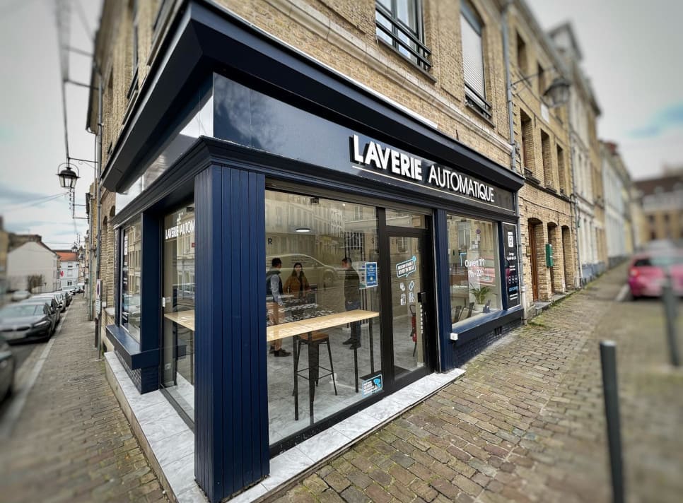 A laundry shop front with a vibrant blue door and expansive windows, enhancing its appeal to passersby.